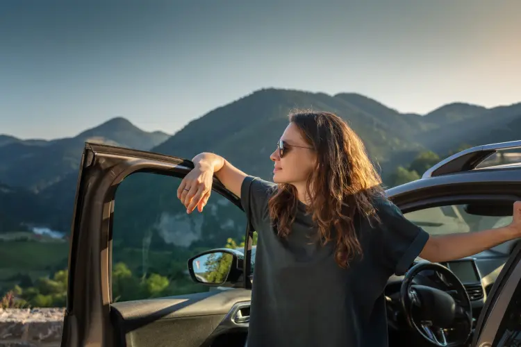 Young woman traveling by car in the mountains, summer vacation and adventure