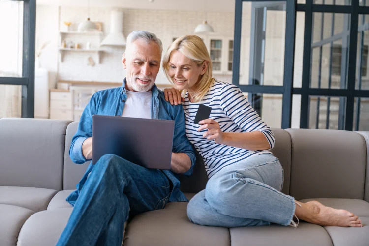 older couple on sofa with a computer getting a car refinance and warranty quote online