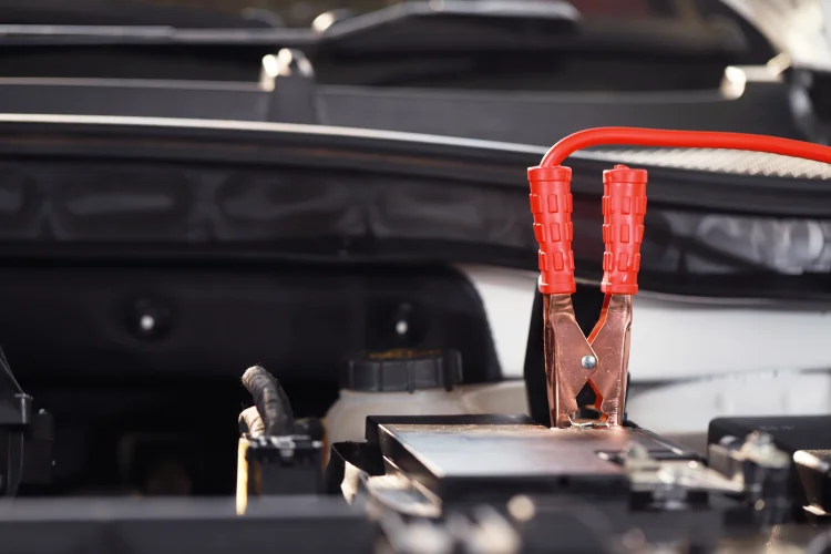 positive end of a jumper cable attached to a car battery