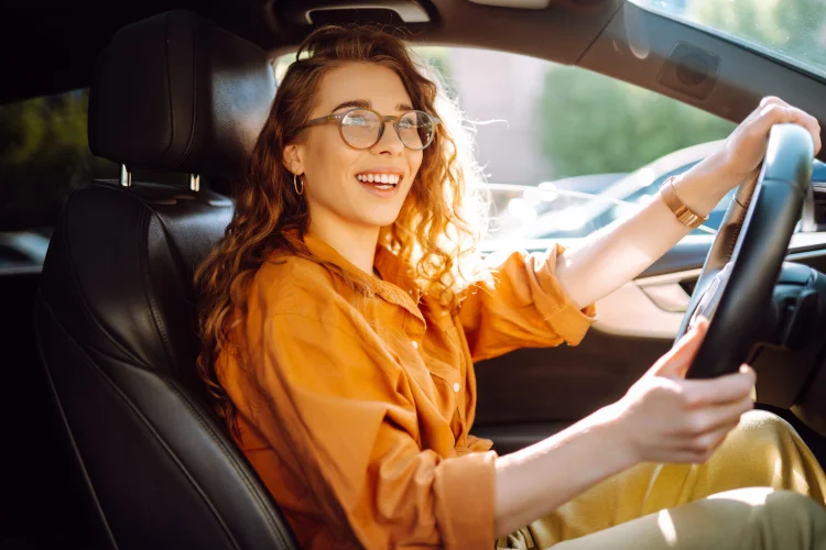 woman in orange shirt driving a car that is covered by an extended warranty