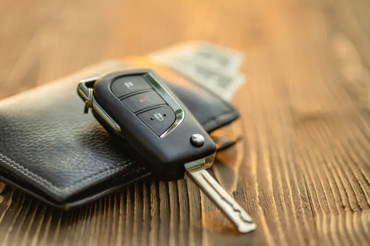 Car key on top of a wallet on a wooden table