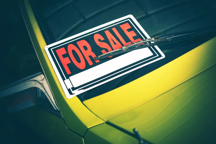 green used car with for sale sign in the front window