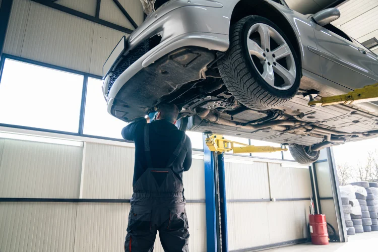 Car with a power train warranty on a lift in a garage being inspected by a mechanic