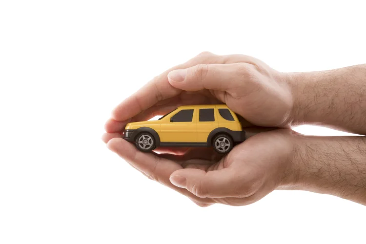 yellow toy car being cupped by two hands
