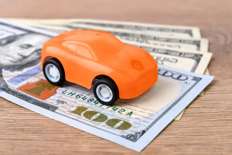 Orange toy car on stack of $100 bills