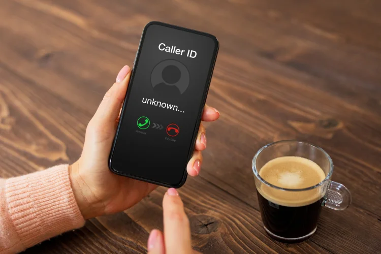woman drinking coffee getting a warranty robocall on her iphone