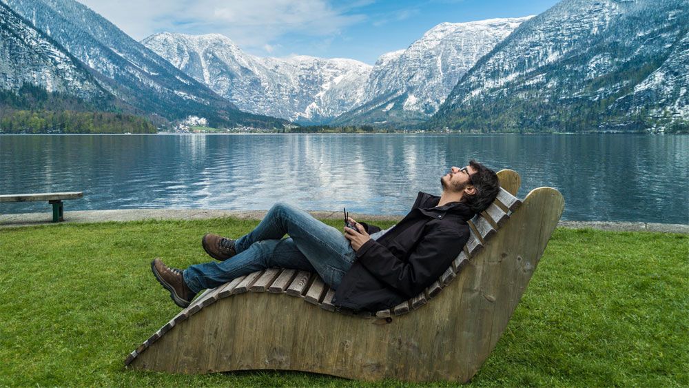 a man sitting on a bench by the lake