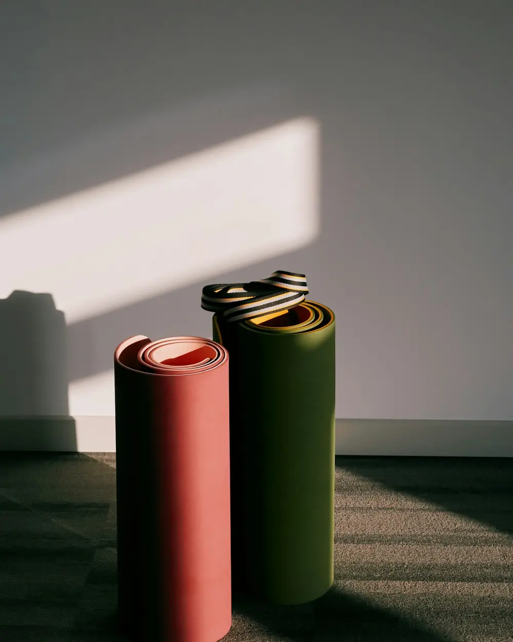 Rolled yoga mats standing in sculptural light