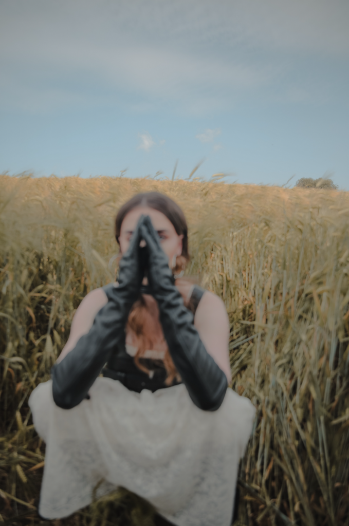 blurry photo of a woman wearing gloves crouching on a field of crops