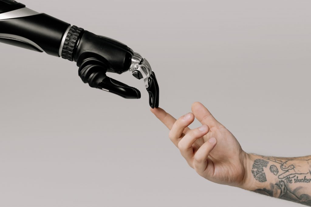 a black robotic hand touching fingertips with a human hand