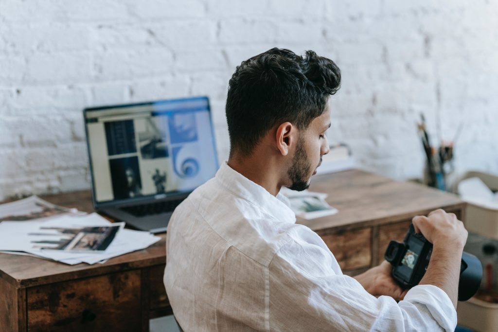 Man in white viewing the images in the camera he is holding