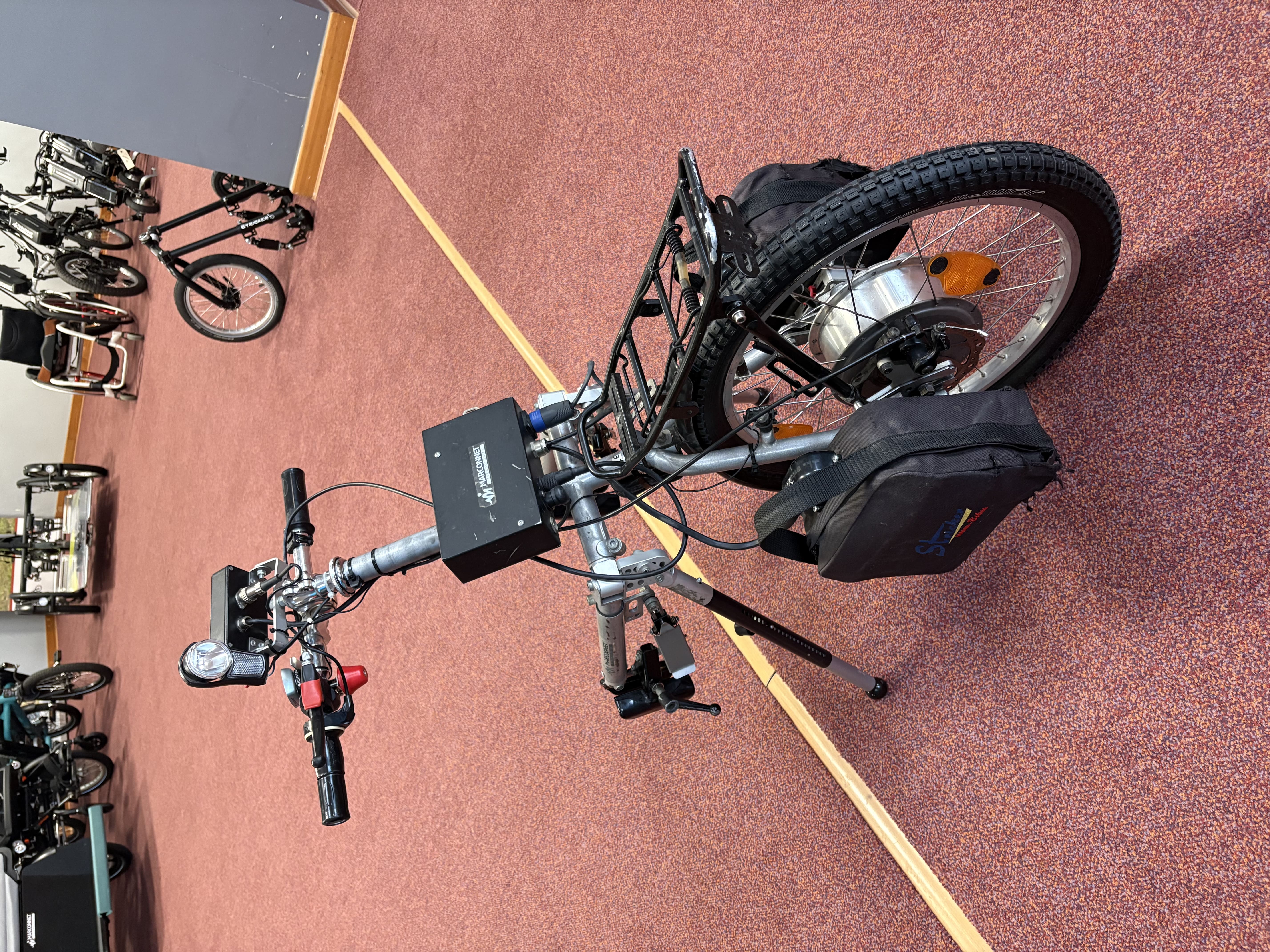 Handbike électrique Stricker Lipo Lomo 20 pouces avec roue avant motorisée, batterie latérale et porte-bagages, vue trois-quarts avant