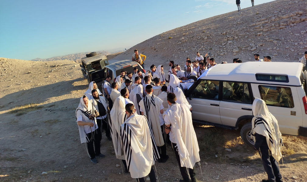 קבוצת מטיילים עטופי טליתות בסיור בר מצווה במדבר