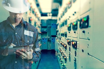 Technician with a tablet inspecting an electrical switchgear room