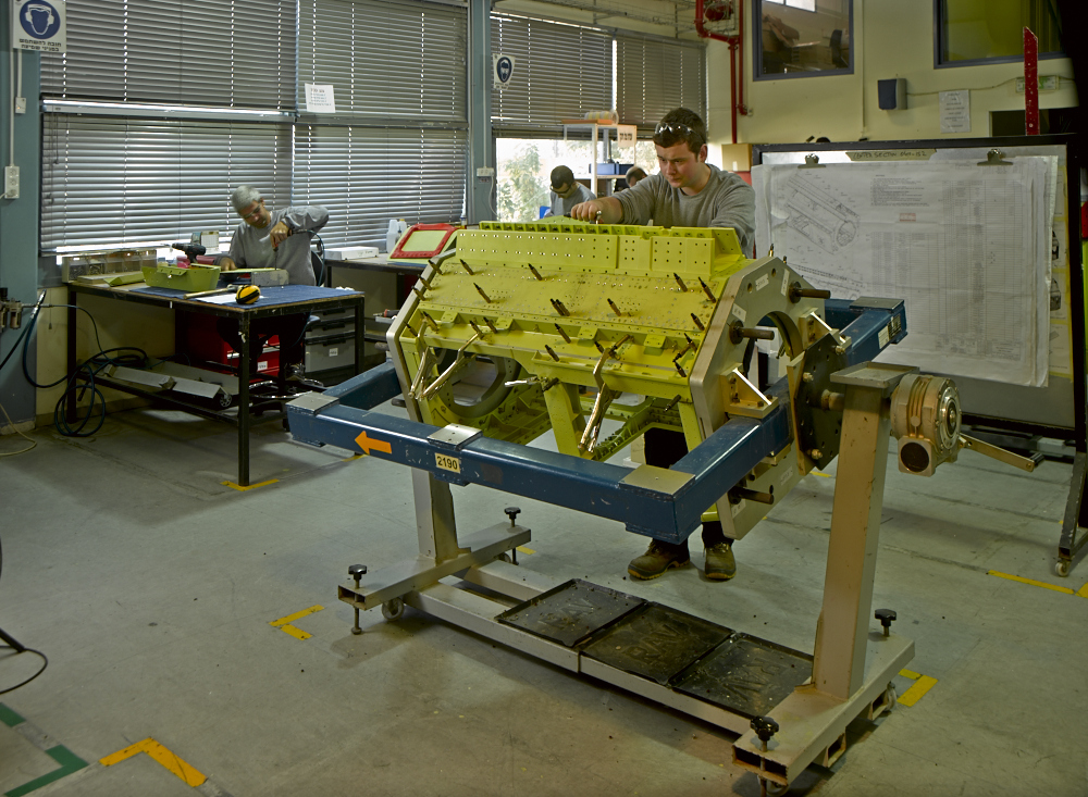 Yellow airborne pod section on an assembly jig