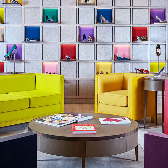 Yellow sofa and round wooden table for customers at Malono Blahnik, Selfridges