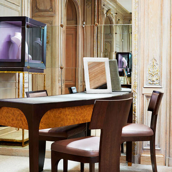 Close up of elegant seating area. Display case of jewellery and mirrors are in the distance.