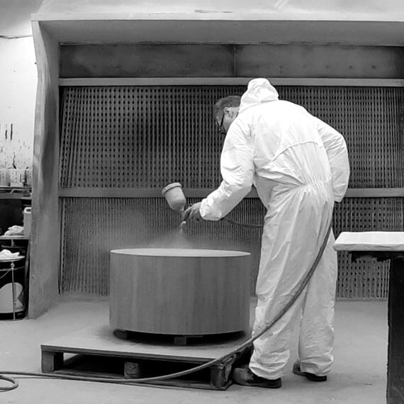 Man in protective clothing, spraying wooden table
