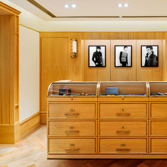 Light coloured wooden display units with nine draws and glass topped display case.