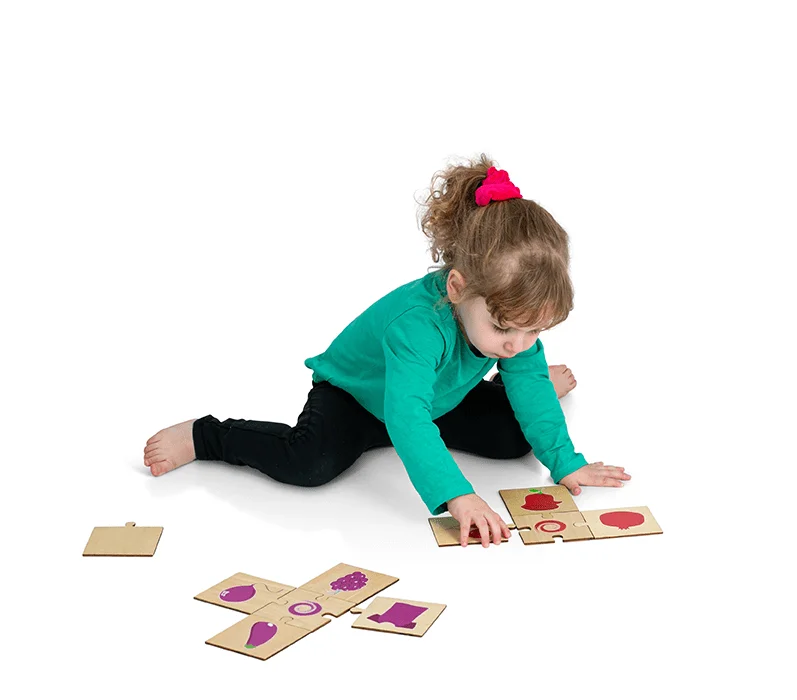 A toddler assembling a Doron Layeled wooden puzzle