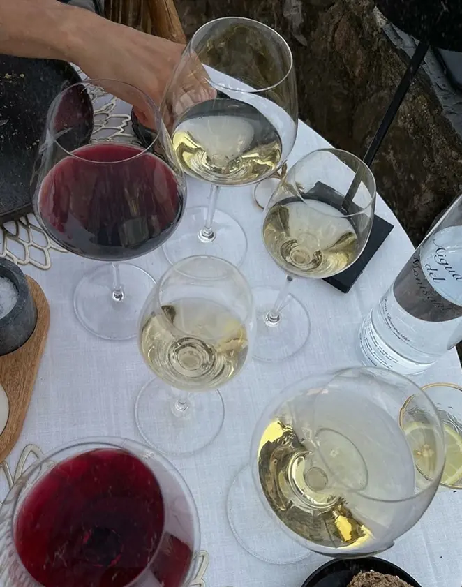 Verres de vin rouge et blanc disposés sur une petite table en extérieur, ambiance conviviale et détendue.