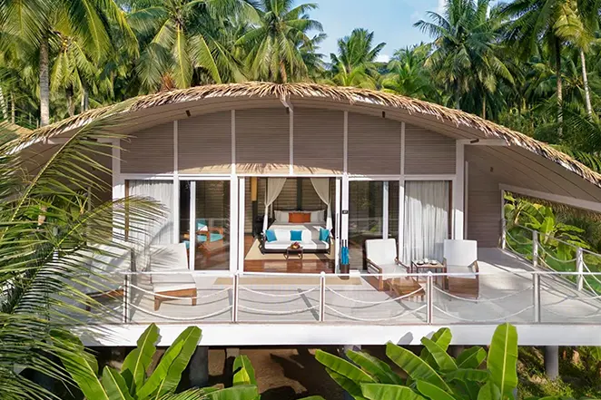 Villa tropicale du Taj Exotica Resort & Spa, nichée parmi les palmiers avec toit en chaume et terrasse privée.