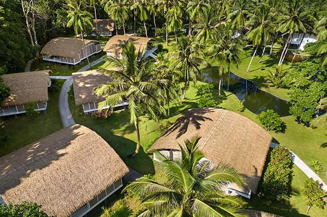 Vue aérienne des villas du Taj Exotica Resort & Spa, Andamans, avec toits en chaume au cœur de la végétation tropicale.