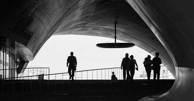 Silhouetted figures in a modern architectural walkway. Kaohsiung City, Taiwan.