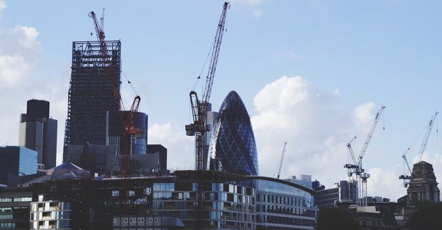 Iconic London skyline featuring skyscrapers and construction cranes on a clear day.