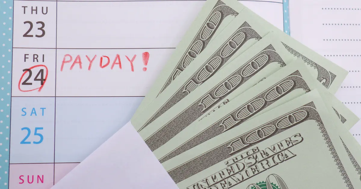 Calendar marked with payday next to an envelope filled with dollar bills, symbolizing salary payment and cost considerations for remote workers.