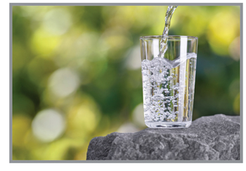 Clean glass of drinking water sitting on a rock