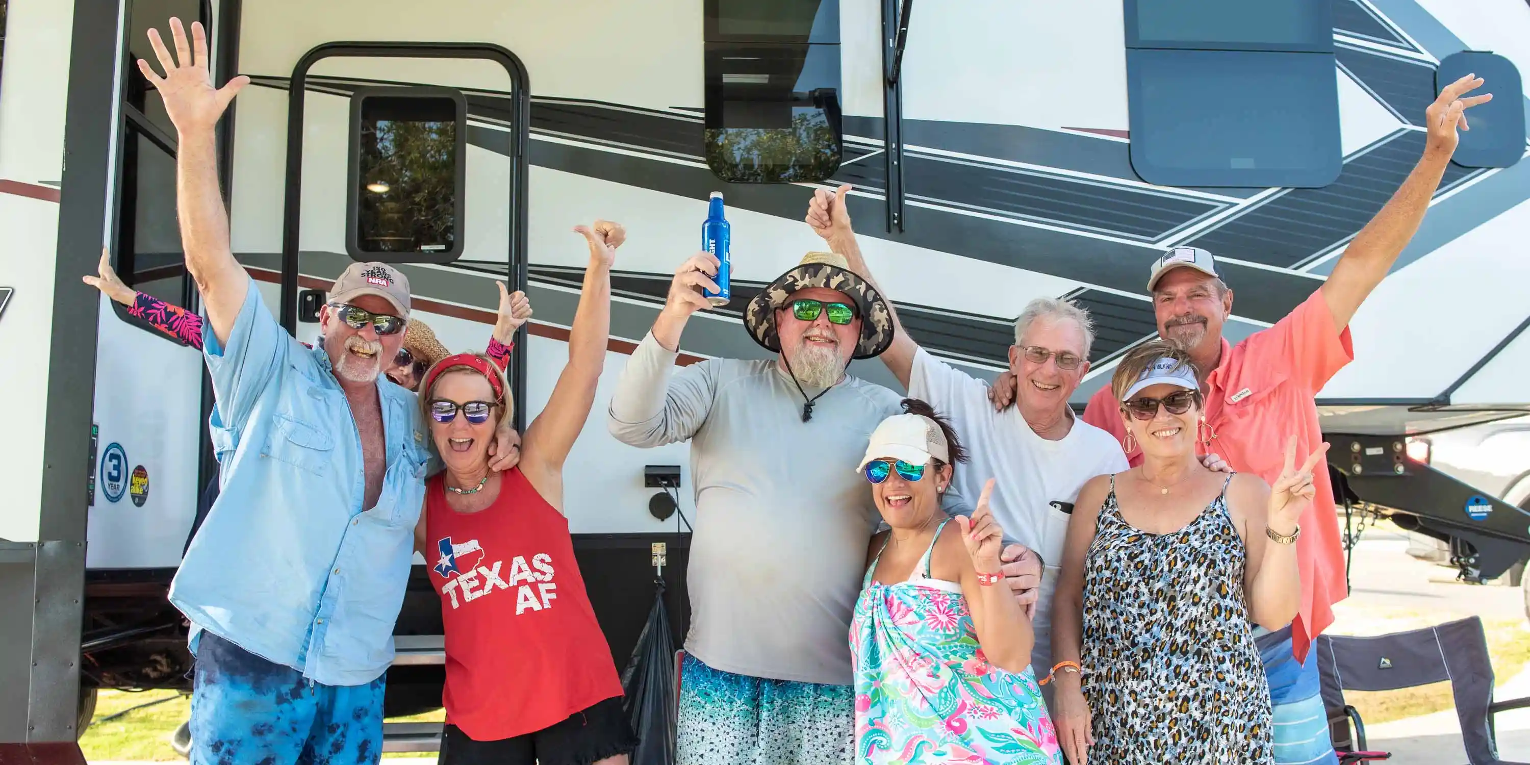 A group of happy guests at Camp Fimfo Texas Hill Country, smiling for a photo in front of an RV