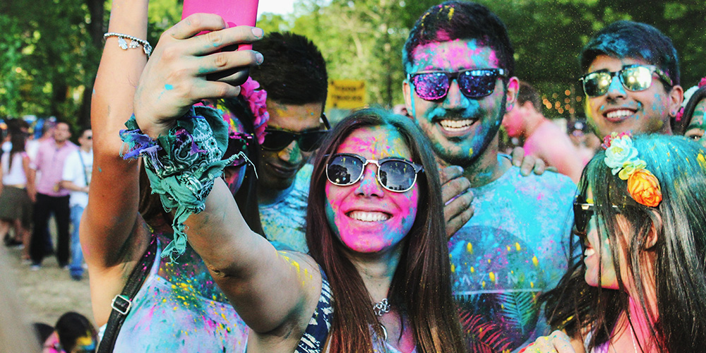 People smiling with color on their clothes after participating in a color run.