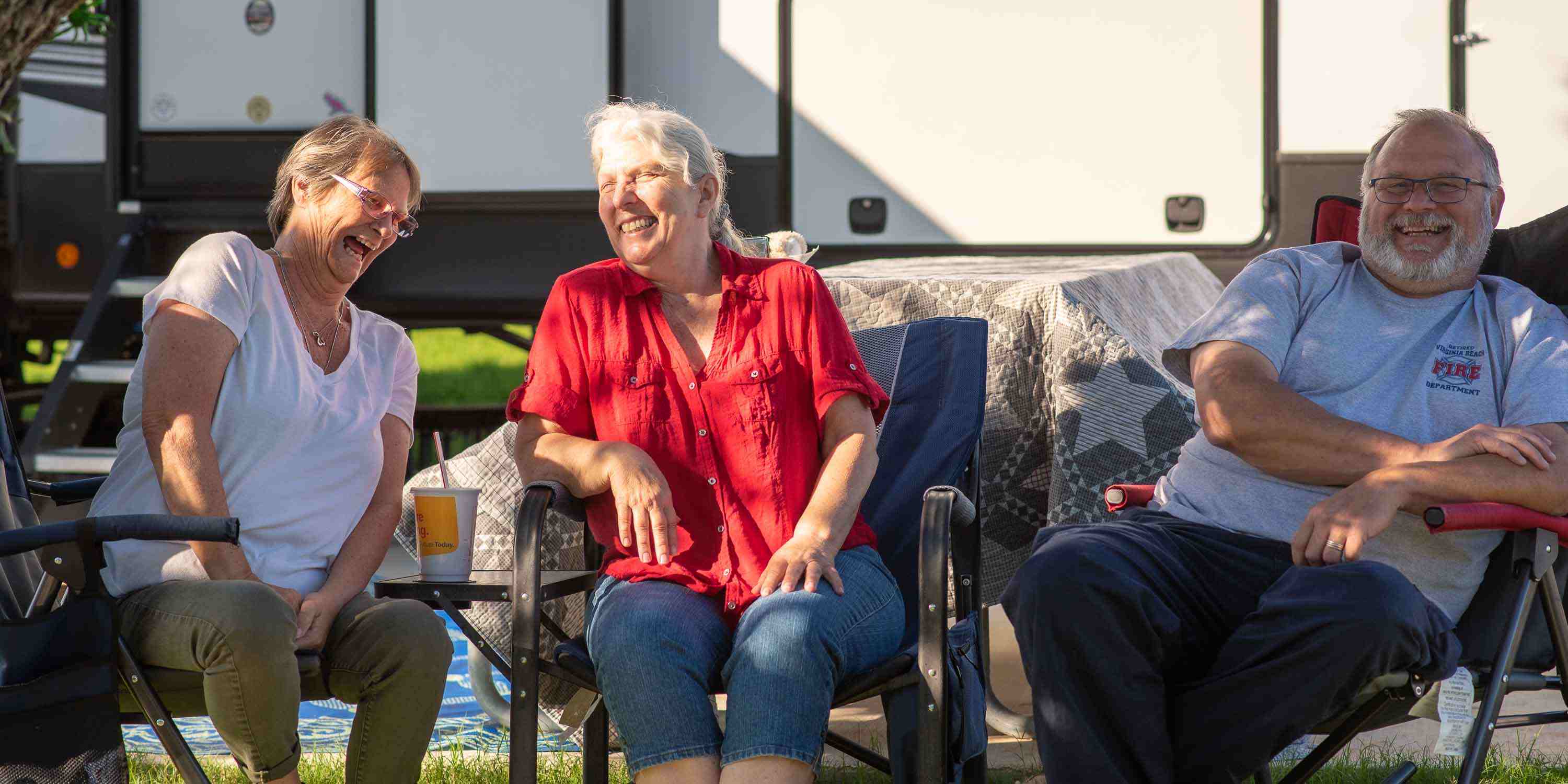 Happy campers sitting in chairs at their long term campsite at Camp Fimfo