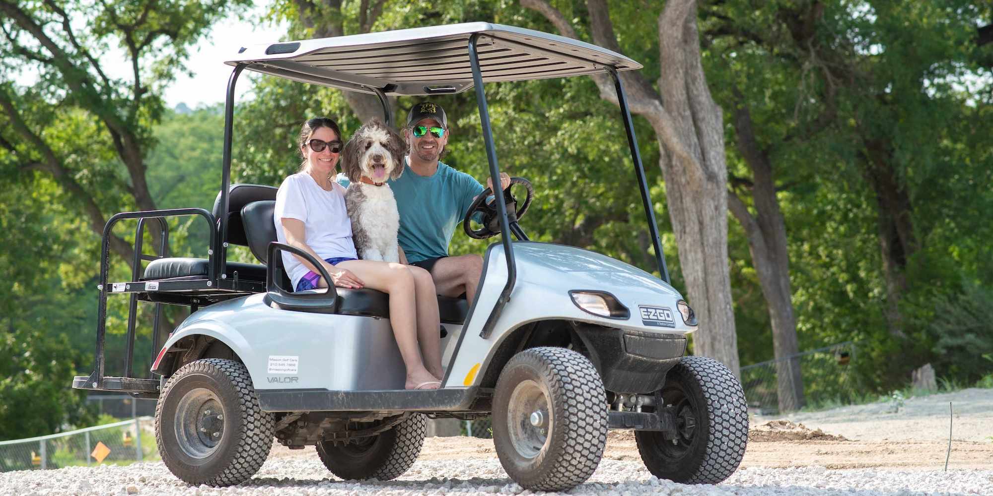 A couple in a golf cart add-on with their dog at Camp Fimfo