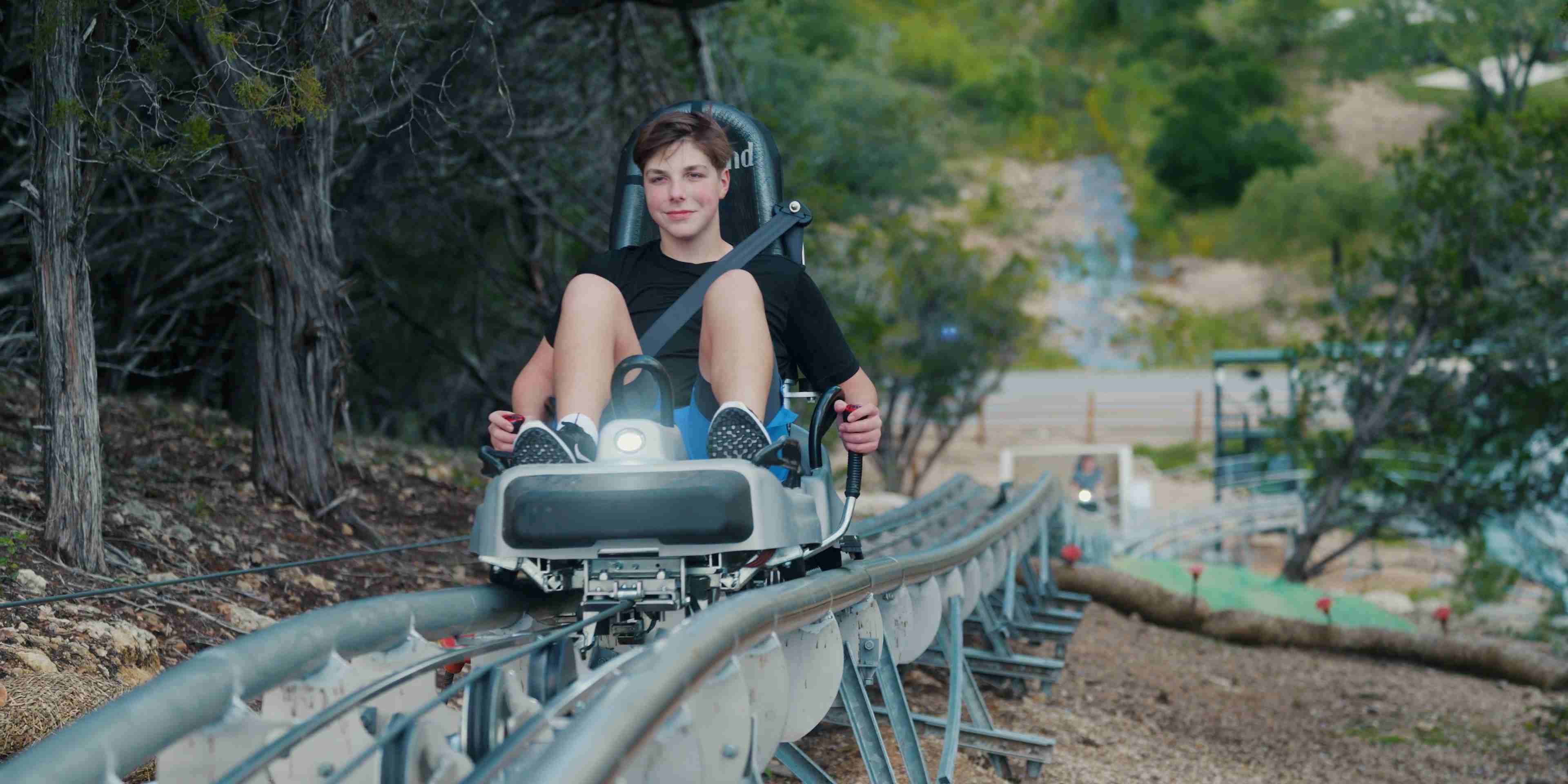A happy guest riding The Cliff Carver at Camp Fimfo, the only alpine coaster in Texas