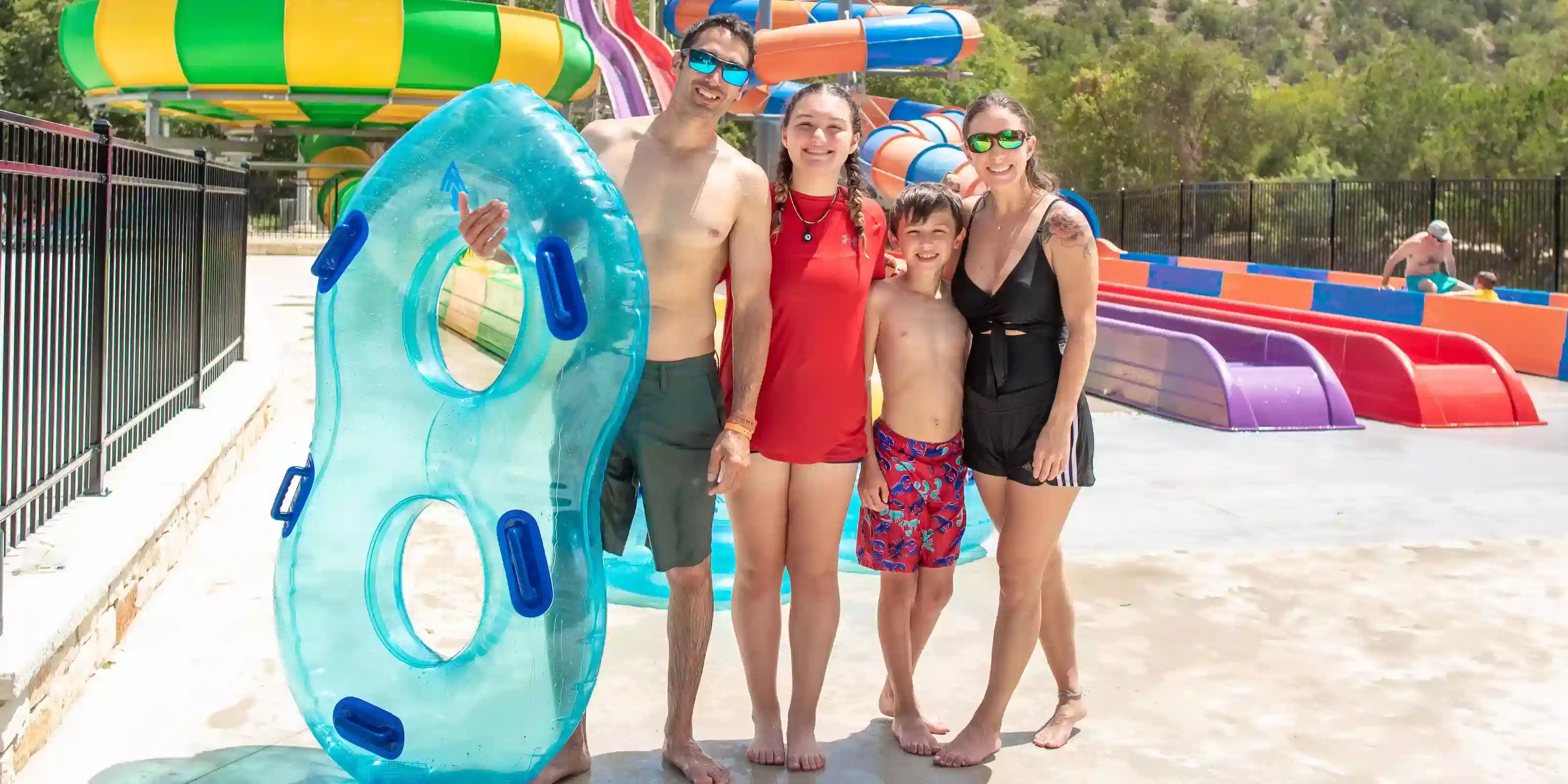 A family holding tubes in front of the water slides at Camp Fimfo