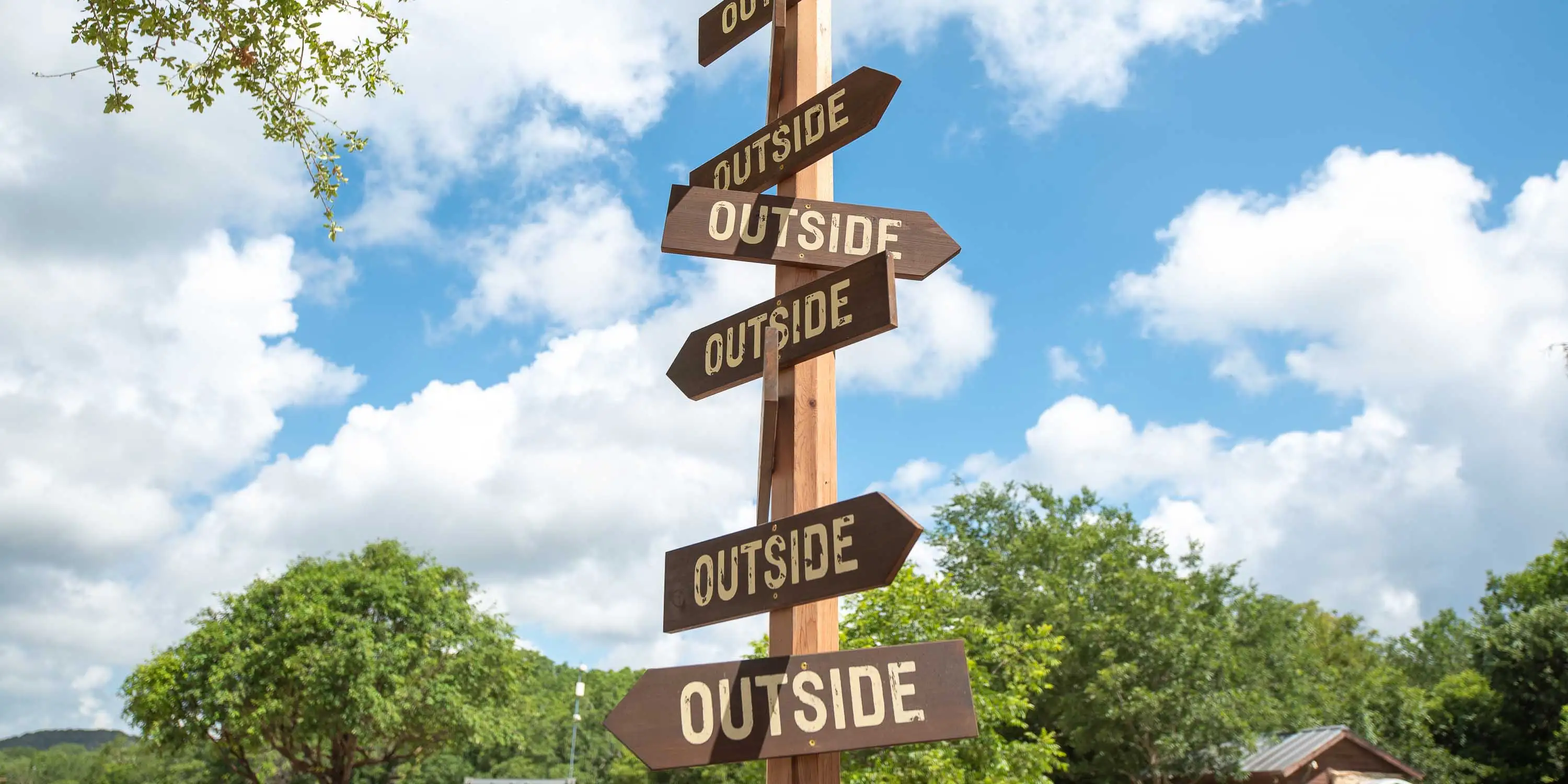 A tall sign at Camp Fimfo that has arrows saying "outside" pointed in all directions