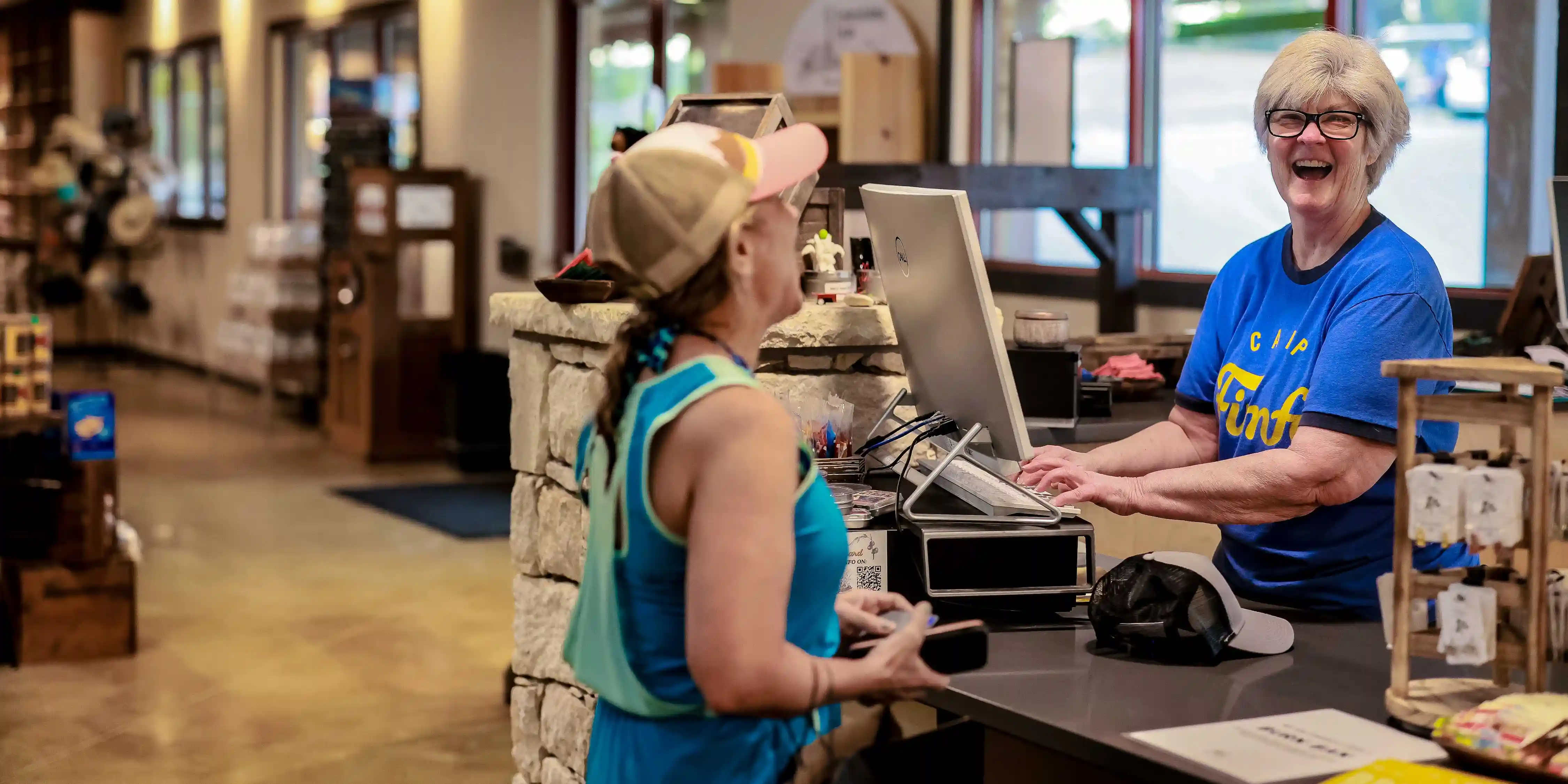 A Camp Fimfo General Store employee ringing up a guest at the cash register