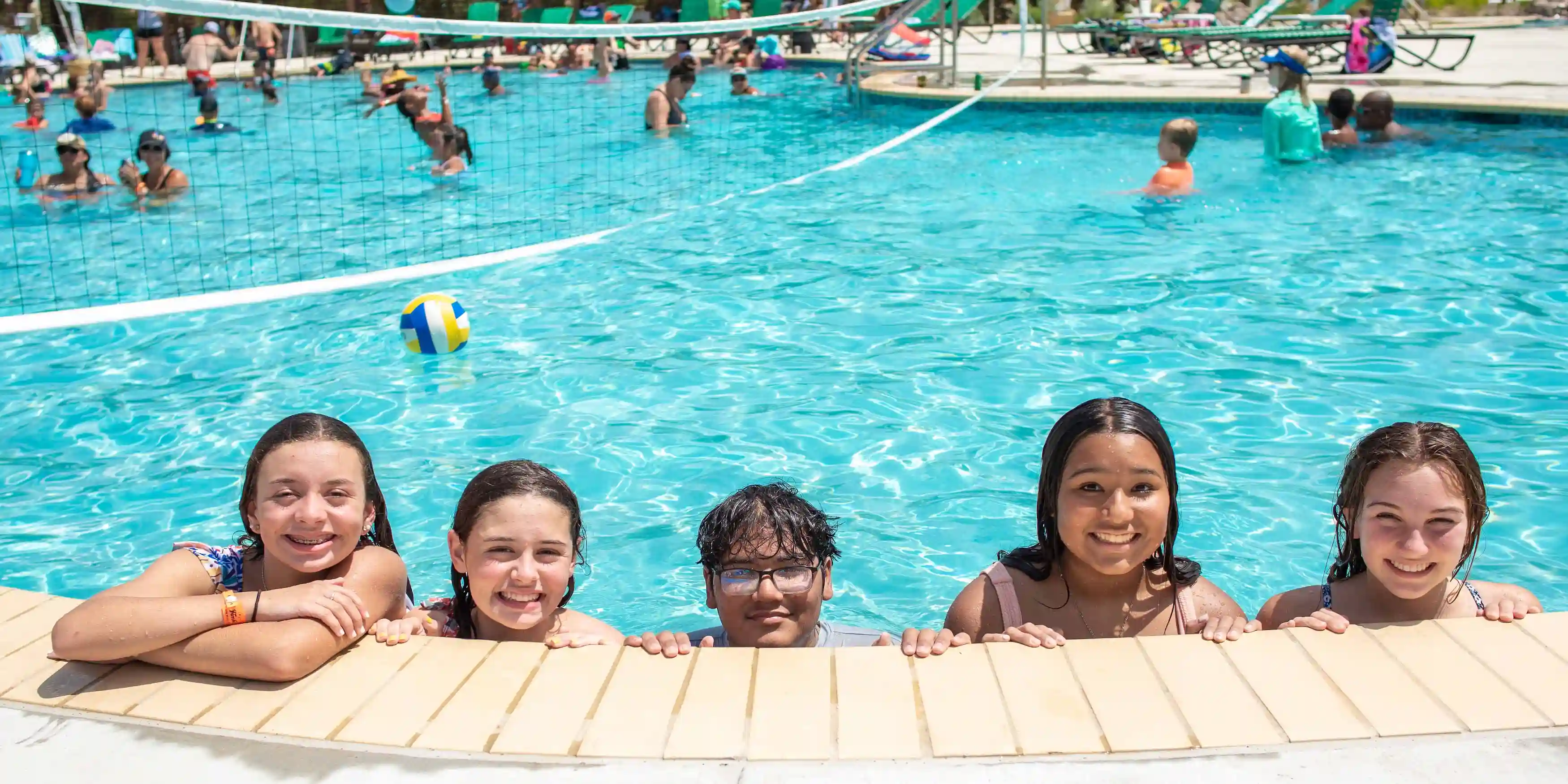 Five young guests posing for a picture in the Camp Fimfo Texas Hill Country pool