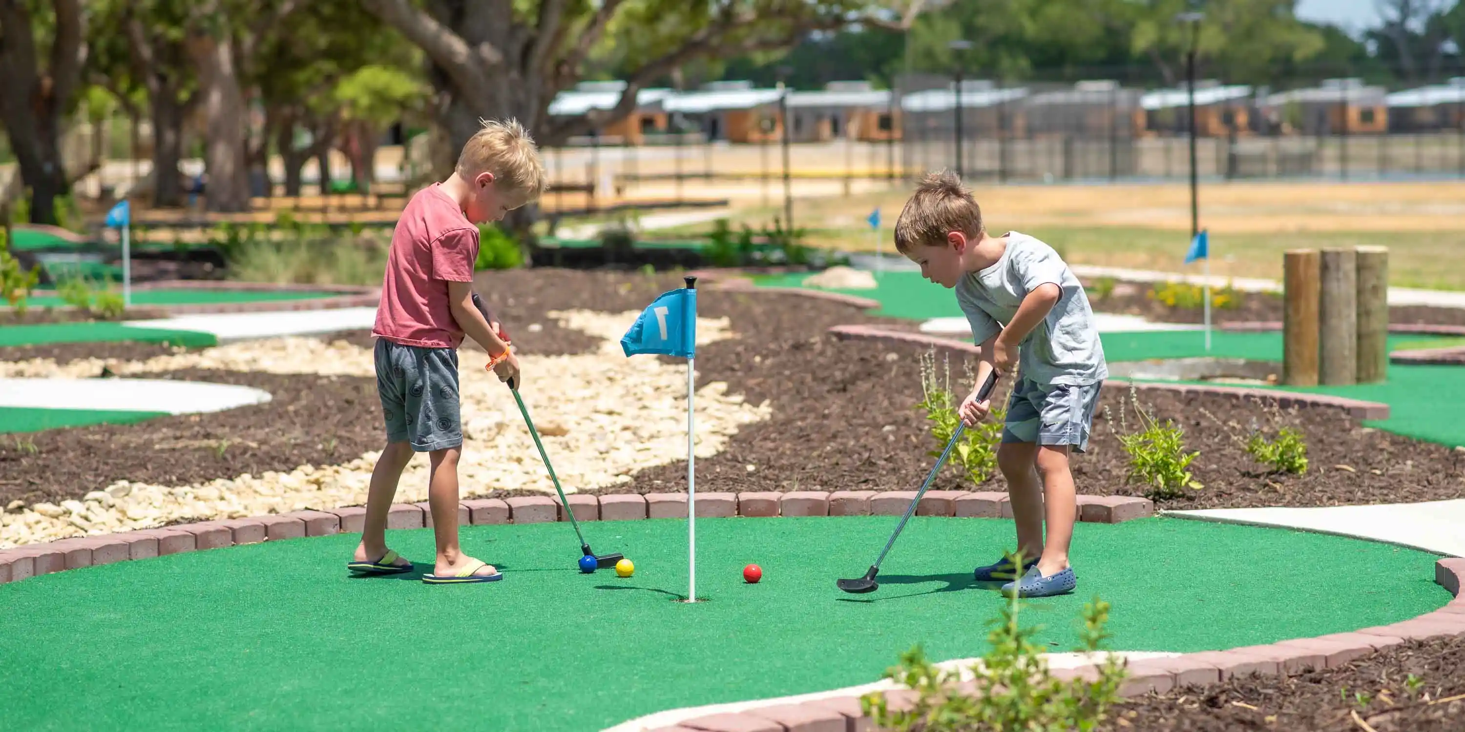 Two children playing mini golf in the summer at Camp Fimfo