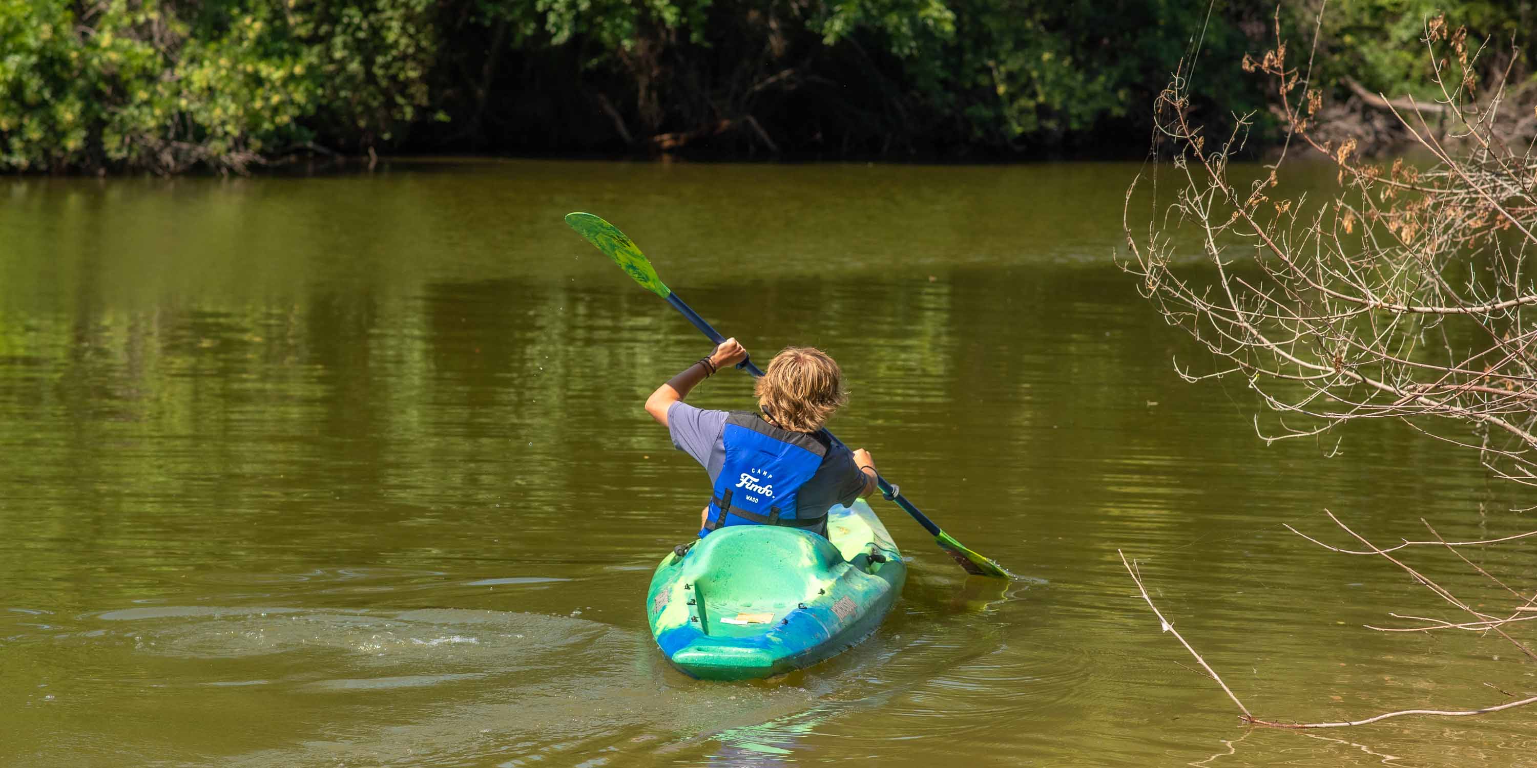 A guest kayaking on the Bosque River at Camp Fimfo Waco