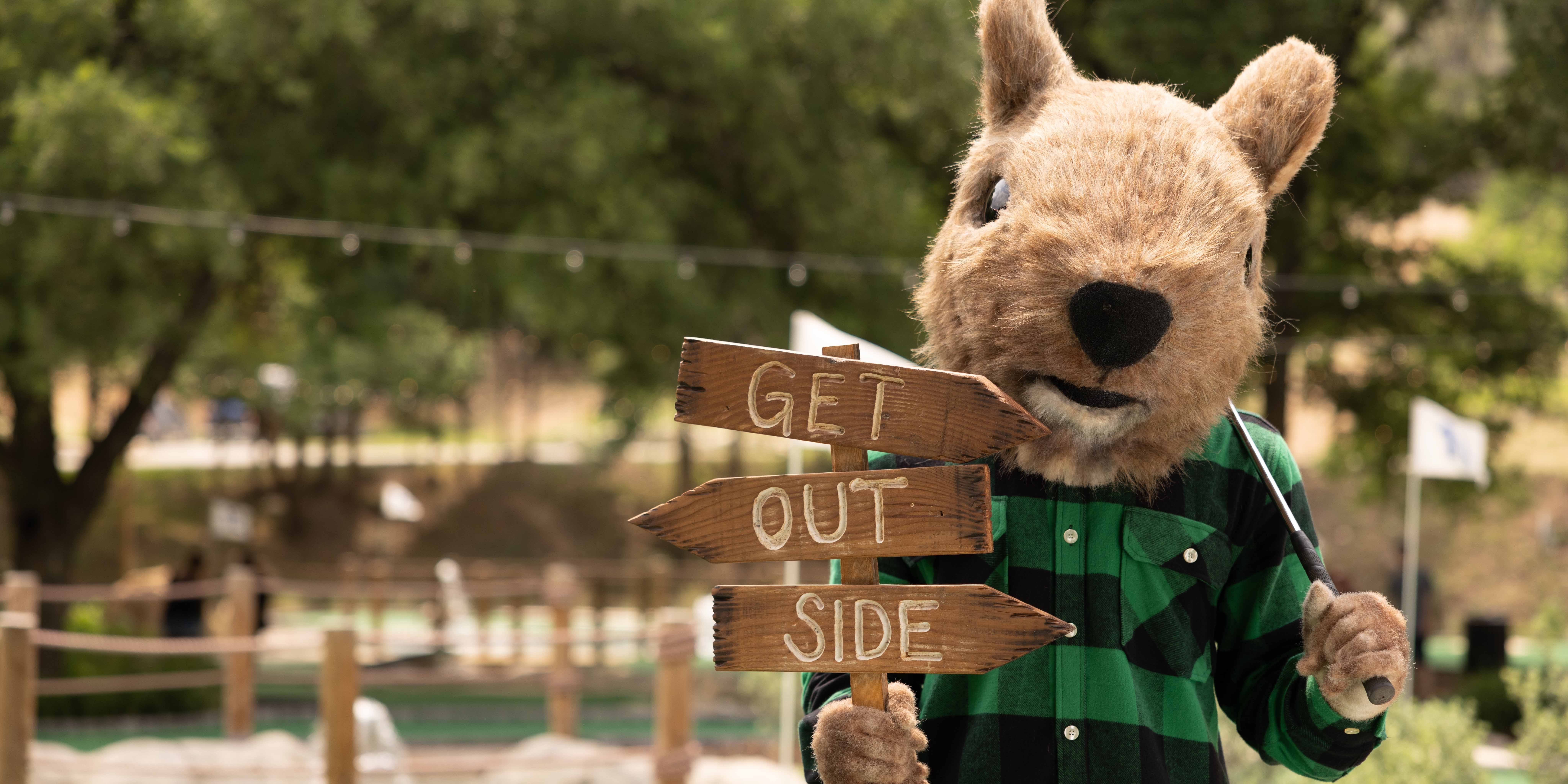 Squirrely, the founder of Camp Fimfo, holding a "Get Outside" sign at Camp Fimfo