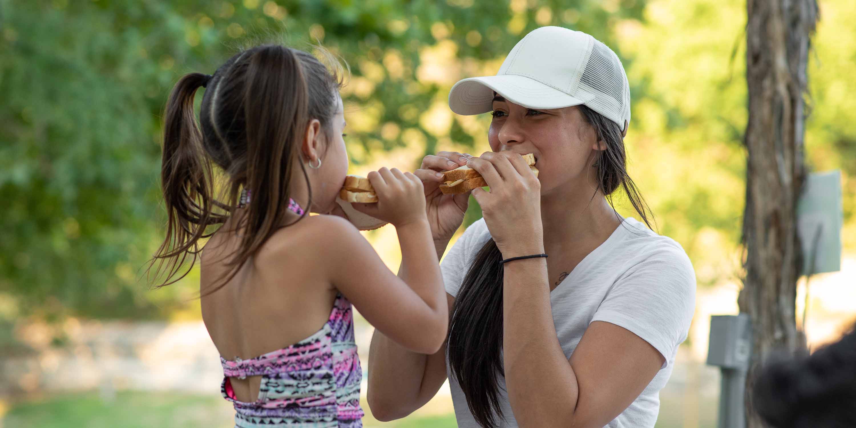 A mother and her daughter having a picnic and eating sandwiches at Camp Fimfo  