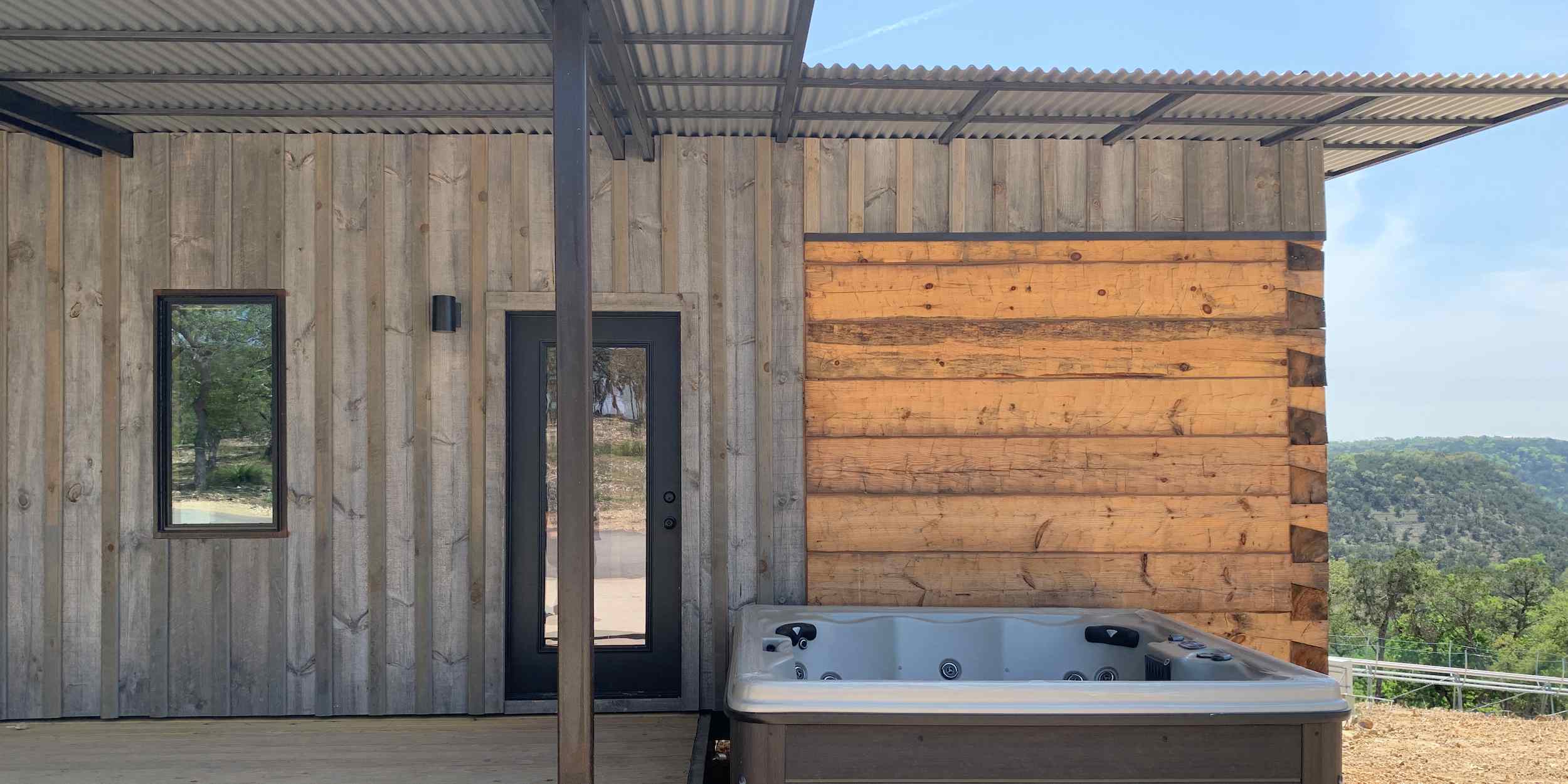 The exterior of a Hilltop Coyote Cabin with a hot tub add-on