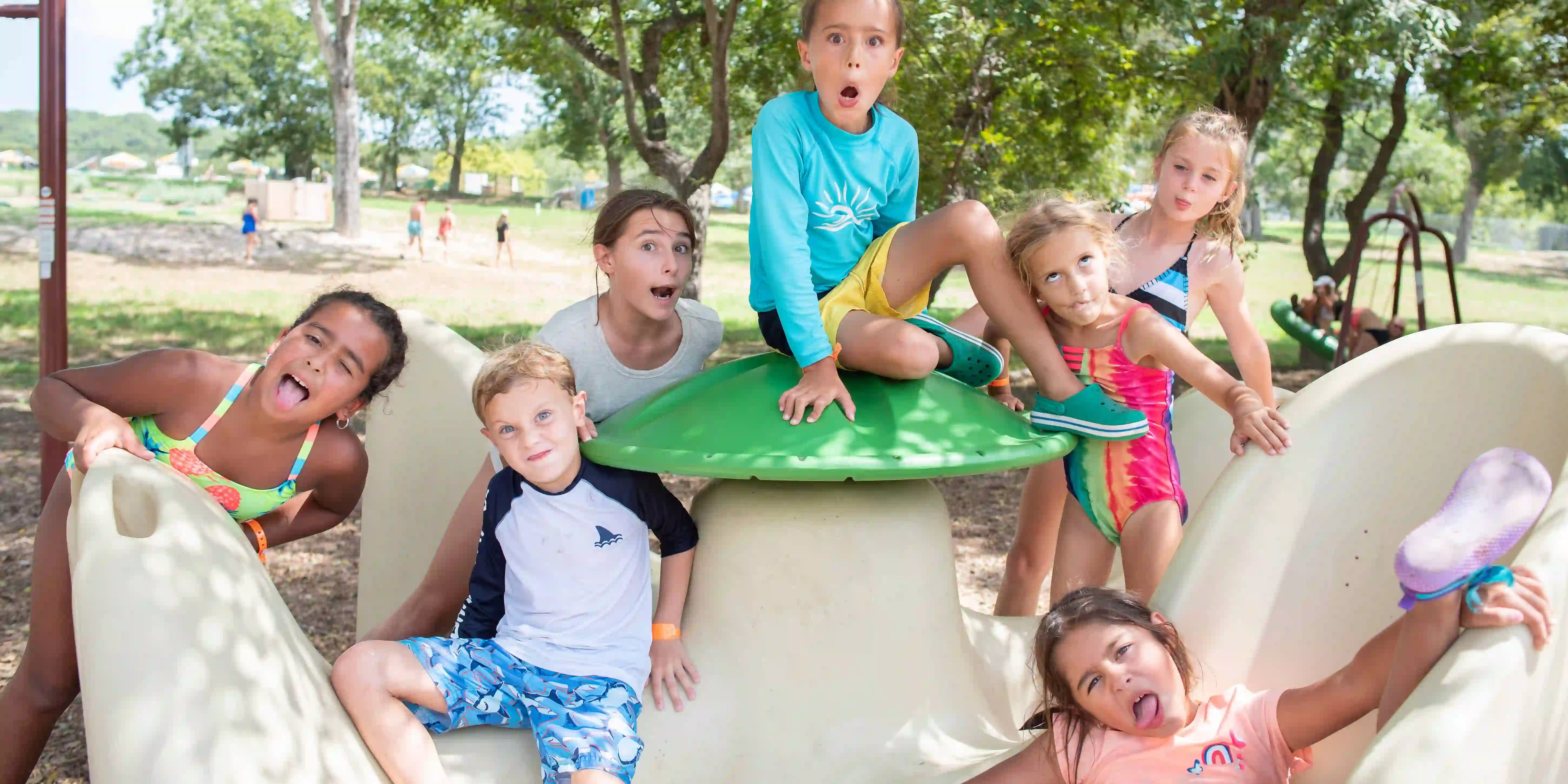 Children playing at the Camp Fimfo playground, making silly faces at the camera