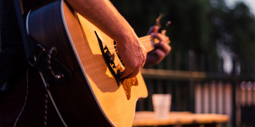 Man strumming the guitar during a mini concert series.