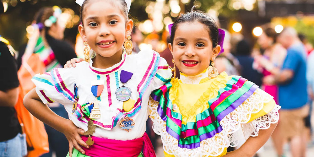 Two girls in festive dresses for Fiesta San Antonio - a great thing to do near Texas Hill Country.