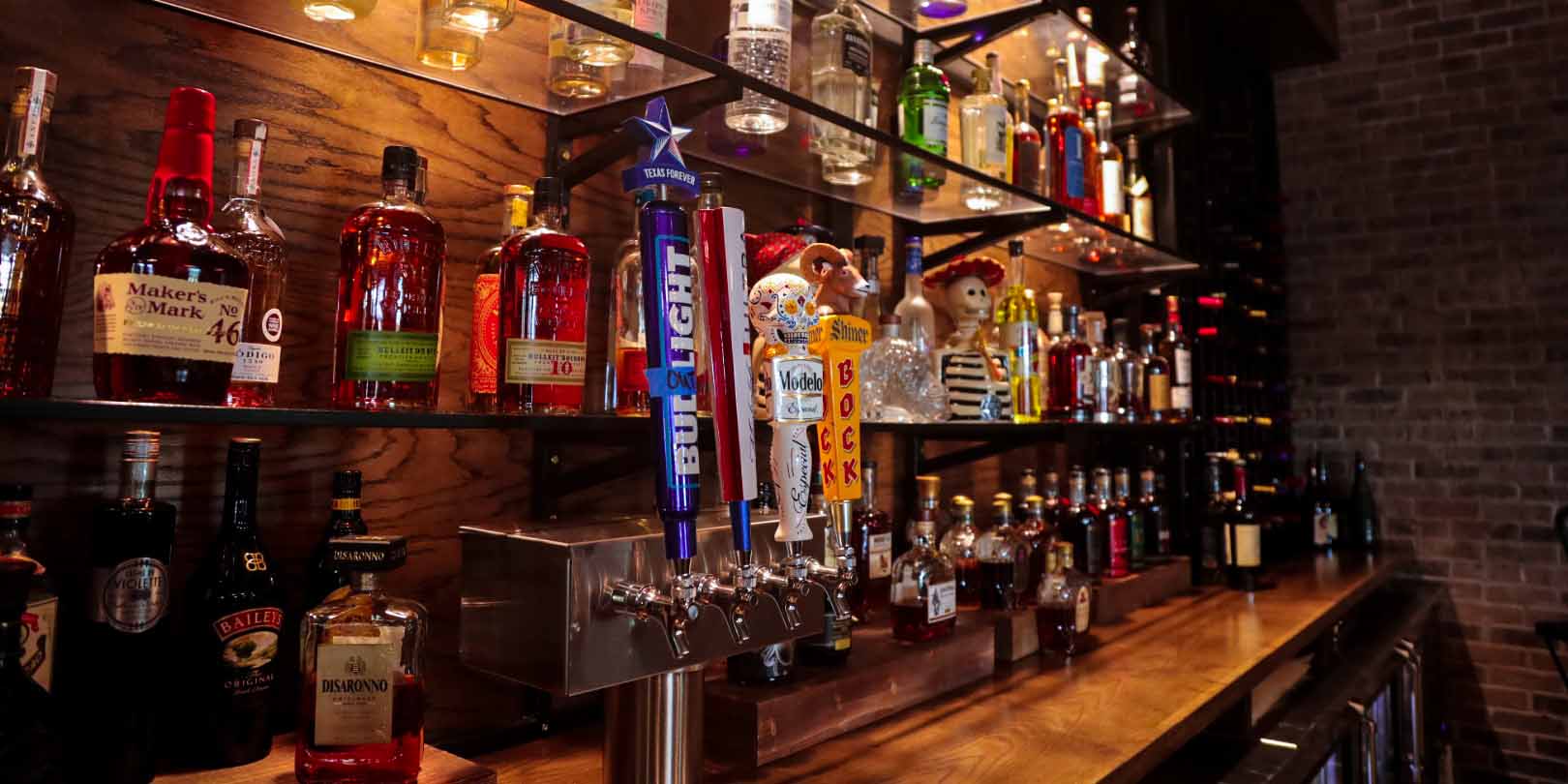 A wall of spirits and tap handles at Squirrely's Tavern at Camp Fimfo Waco