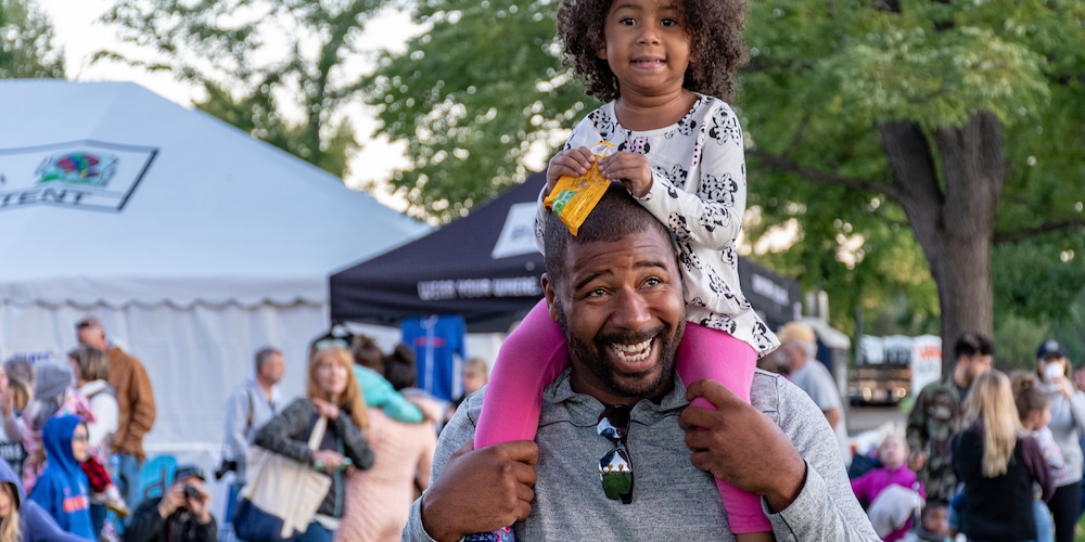 Father and daughter smiling at the Annual Three Rivers Festival - a great event in Fort Wayne!